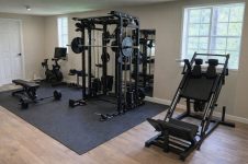 Välutrustat hemmagym med multimaskin, benpress och träningsbänk.